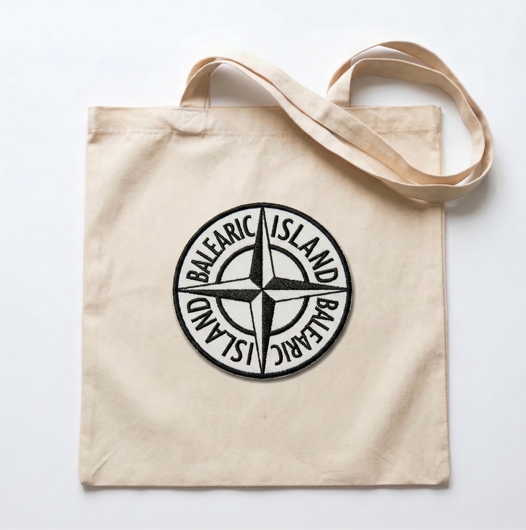 Beige tote bag with a black compass design on a white background