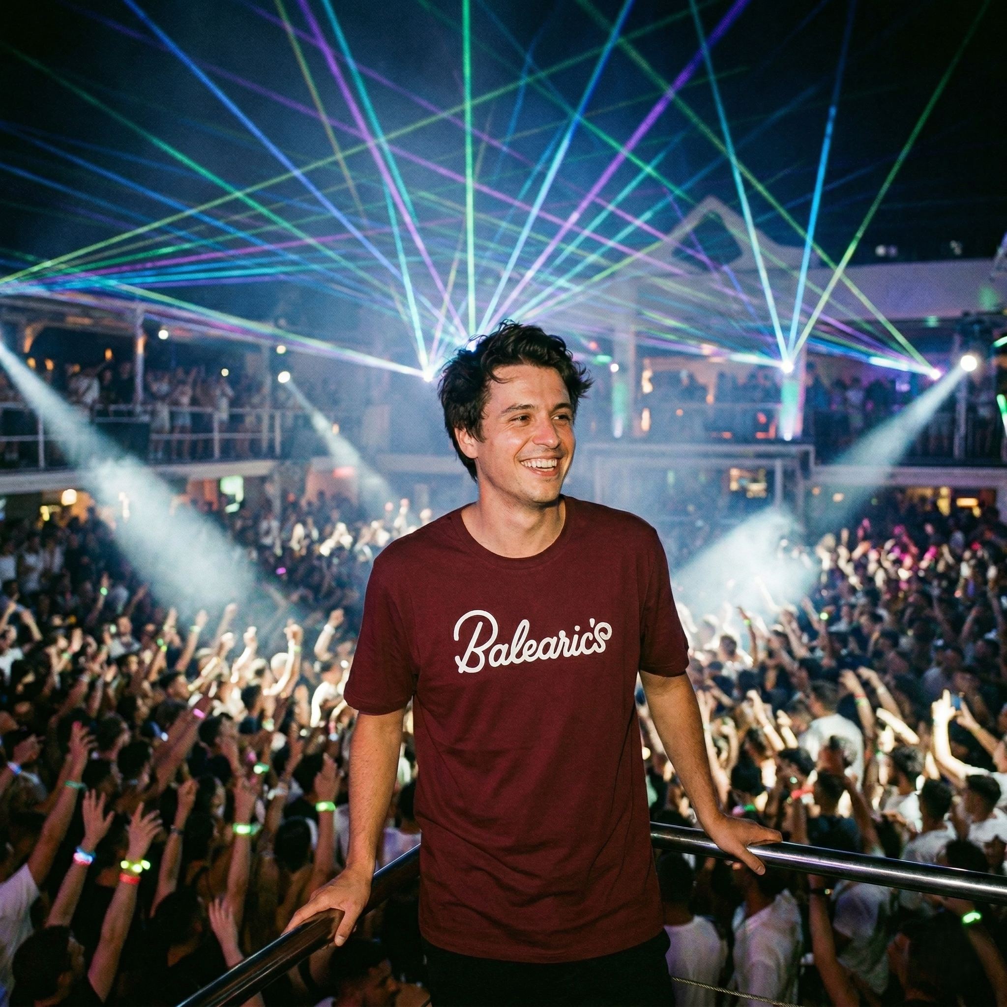 Balearic Blend T-shirt: A vibrant lifestyle photograph captures a smiling man leaning on a balcony overlooking a packed nightclub, wearing the maroon 'Balearic Weekender T-shirt' with its specific parody logo. Overhead, complex blue, green, and purple lasers slice through the dark, smoky air, illuminating the ecstatic crowd.